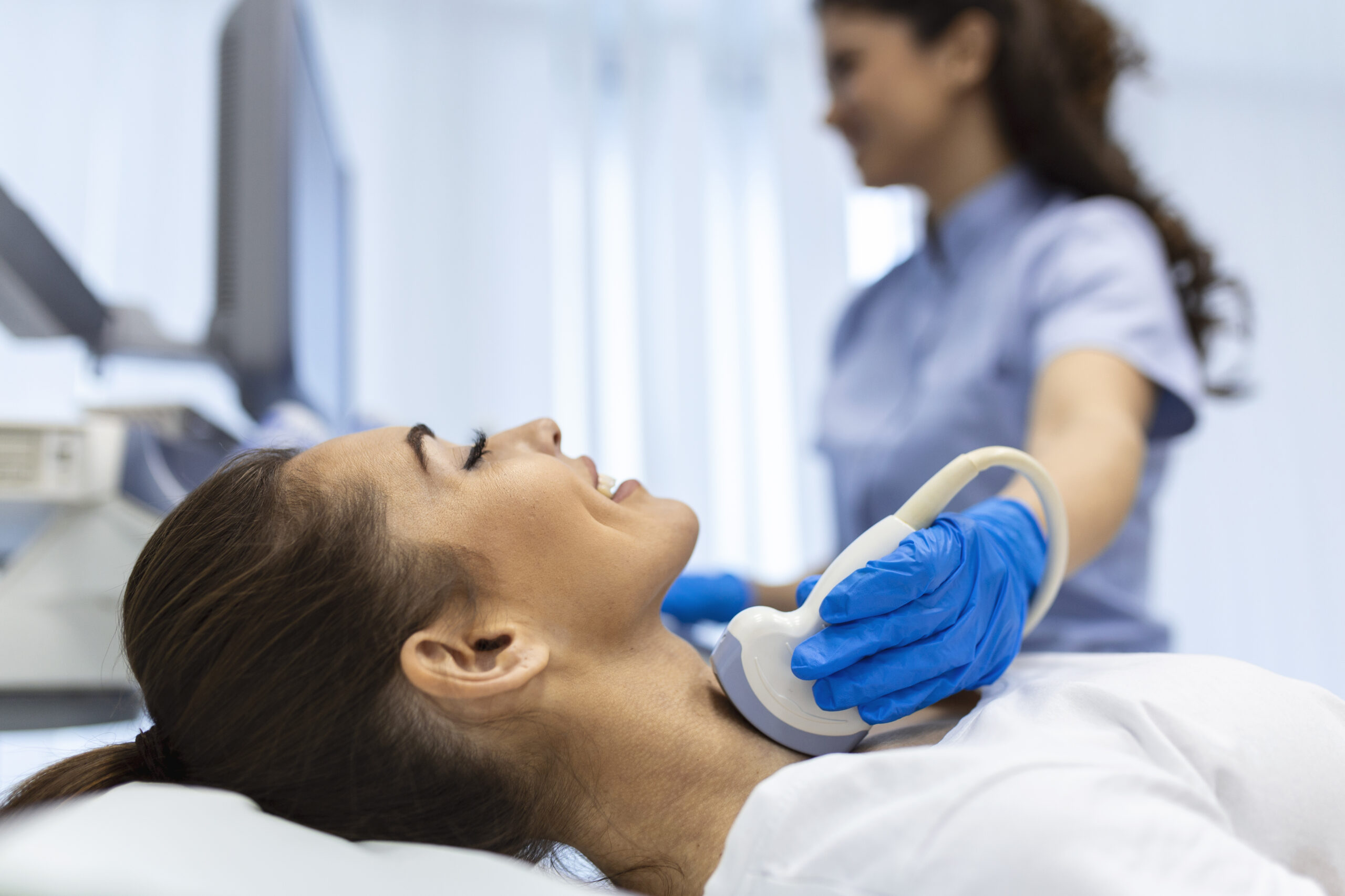 Woman patient receives thyroid diagnostics. Treatment of thyrotoxicosis, and hypothyroidism. Ultrasound diagnostics of the endocrine system and thyroid